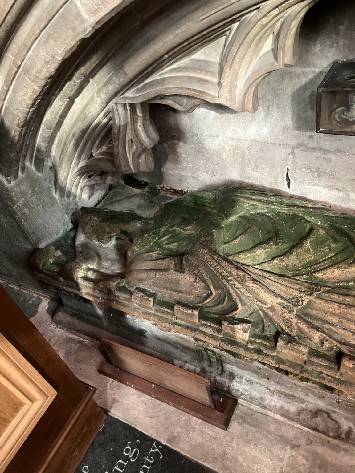 Reclining clerical effigy of Richard de Potesgrave in the chancel at Heckington, with green painted vestments